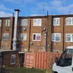 A van is parked in front of a brick building that houses loft insulation installers.