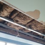 A man installing loft boarding on the ceiling of a room.