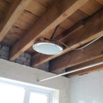 A bathroom with wooden beams and a light fixture.