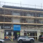 A building with scaffolding in front of it undergoing renovation for loft boarding and spray foam insulation.