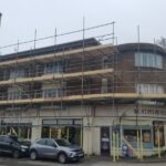 A building with scaffolding in front of it undergoing construction for loft boarding.