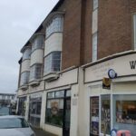 A brick building with a car parked in front of it and loft insulation.