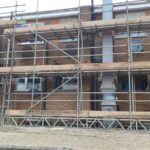 A building under construction with scaffolding around it for loft insulation.