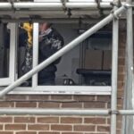 A man looking out of a window with scaffolding during a loft insulation installation project.