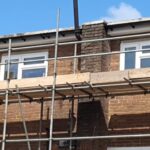 A house with scaffolding on the side of it being renovated by loft insulation installers.