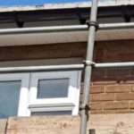 A brick wall with scaffolding and a loft window.