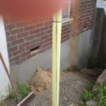 A yellow loft ladder next to a brick wall.