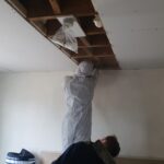 A man is working on loft insulation in a room.
