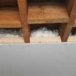 The ceiling of a room with a lot of loft insulation in it.