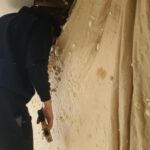 A man is working on a wall in a room, installing spray foam insulation.