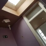 A skylight in a room with purple walls and loft insulation.
