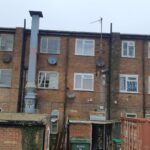 A brick building with many windows and a satellite dish equipped with loft insulation.