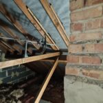 An attic with a wooden floor and a brick wall, suitable for loft boarding installation.