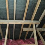 An attic with wood beams and insulation.