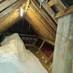 An attic with loft boarding and a sheet on top of it.