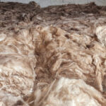 A man is working on a pile of wool for a loft insulation project.