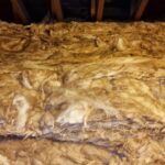 A pile of loft insulation in the attic of a house.