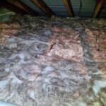 Insulation material covering the floor of an attic, with roof beams visible in the background.
