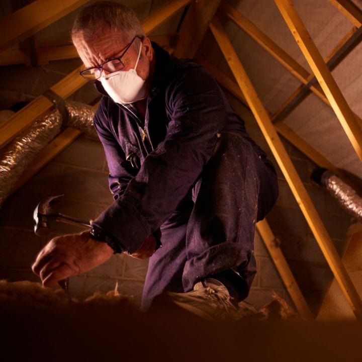 Loft insulation specialist installing or inspecting loft boarding in an attic space.