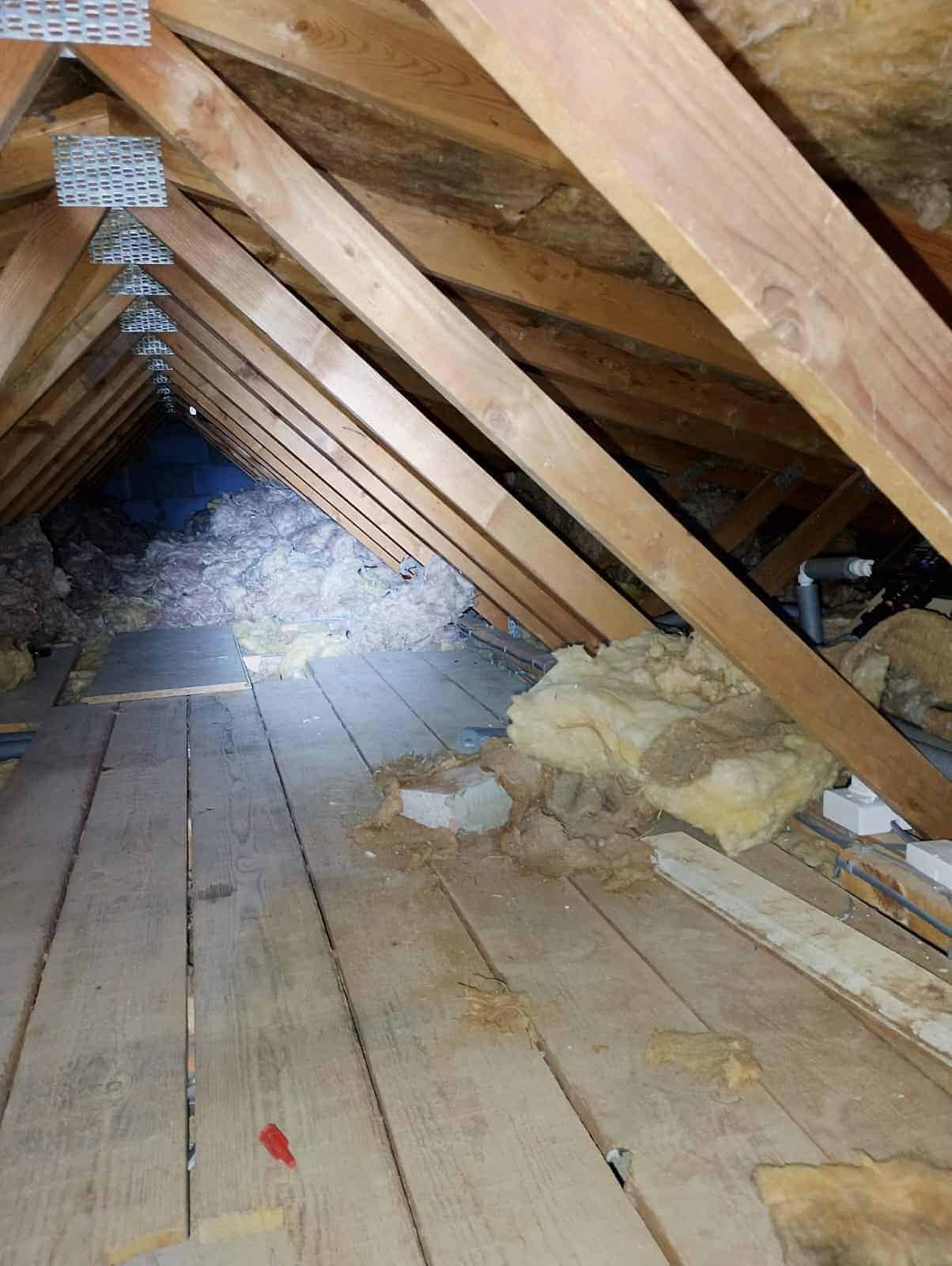 Loft insulation being installed between roof rafters for energy efficiency.