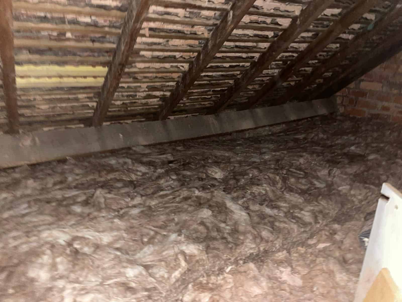 Loft insulation being installed between roof rafters for energy efficiency.