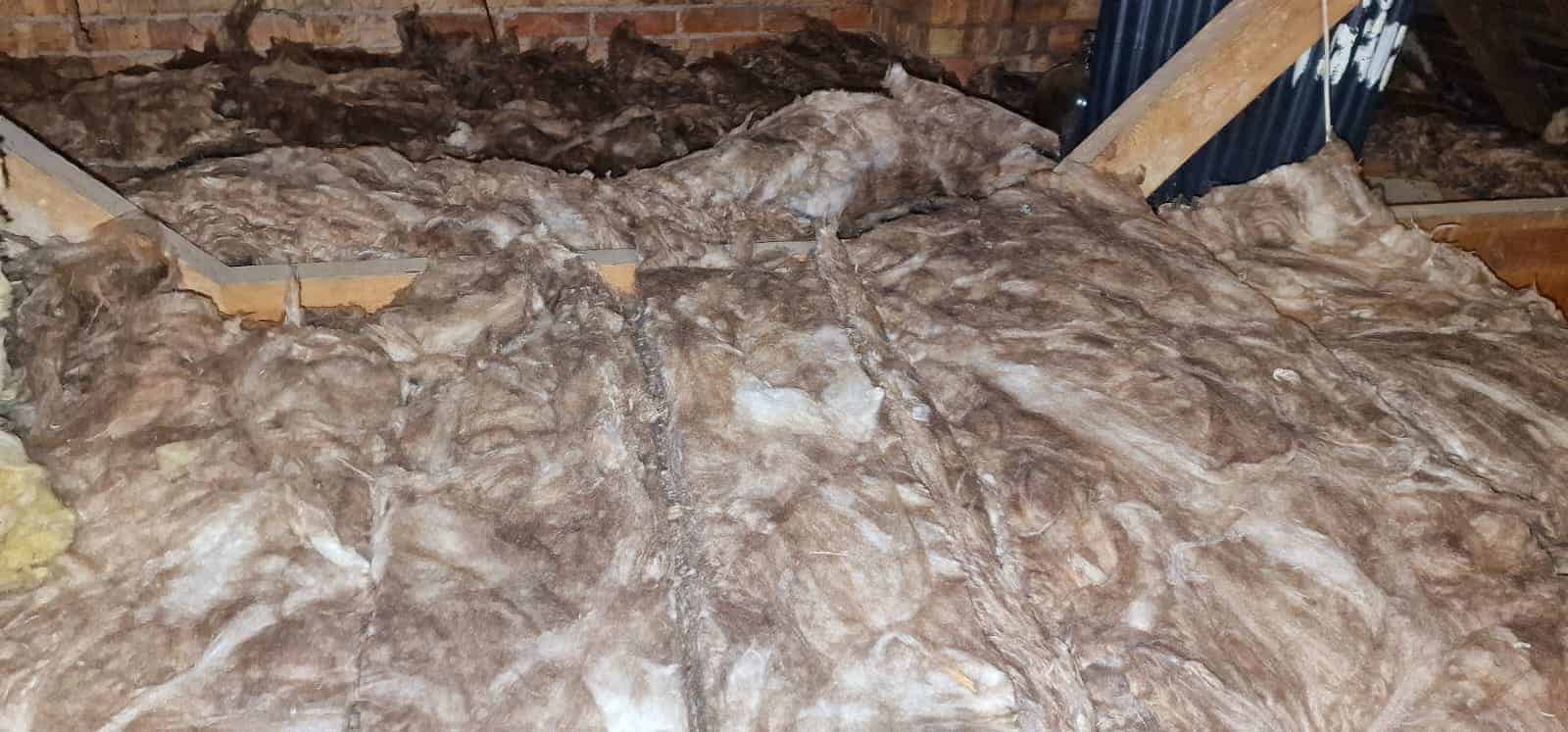 Loft insulation being installed with mineral wool batts in a residential attic.