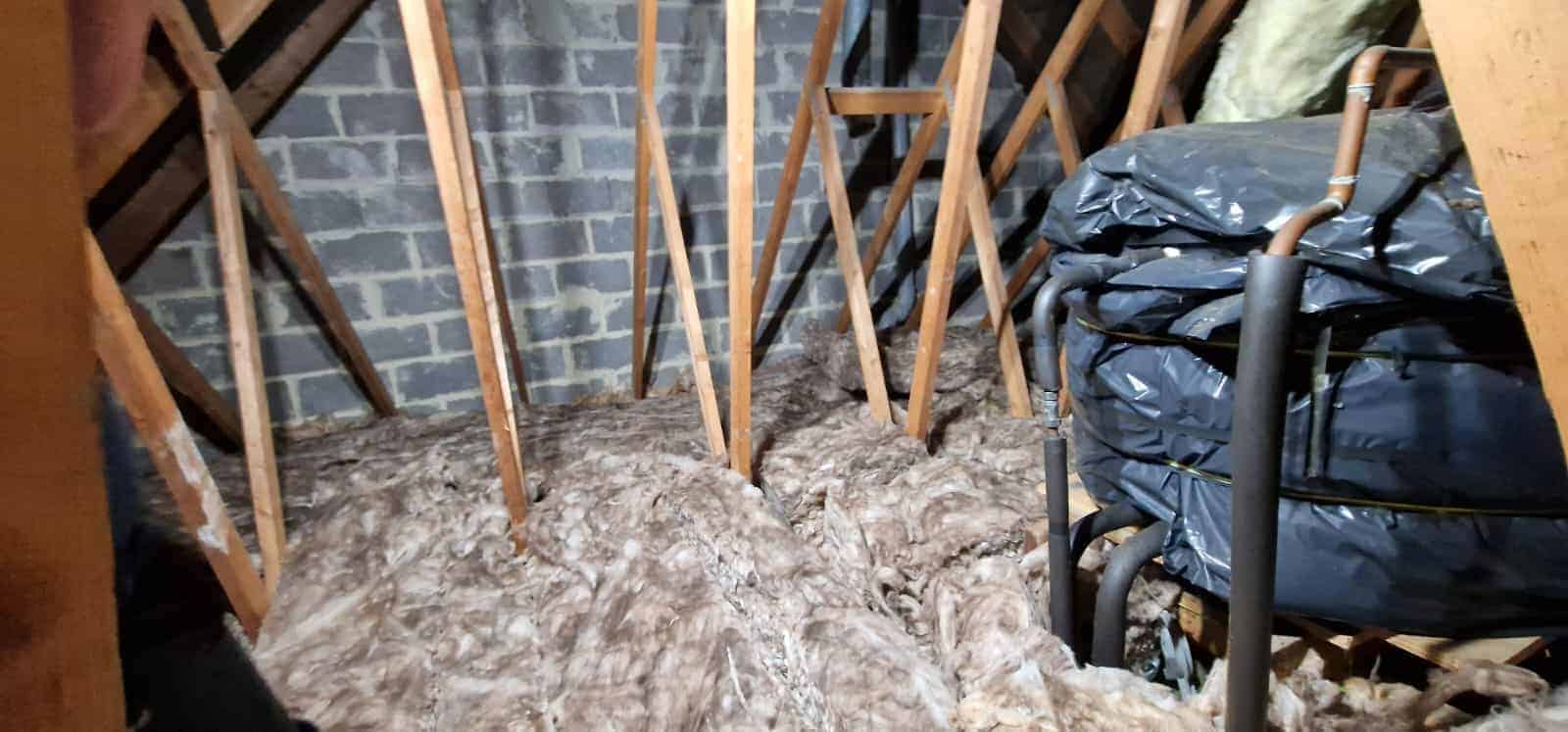 Loft insulation being installed with mineral wool between roof rafters.