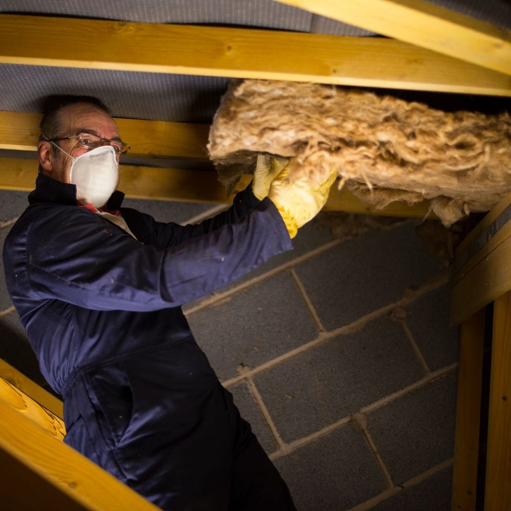 Loft insulation specialist fitting insulation between roof joists.