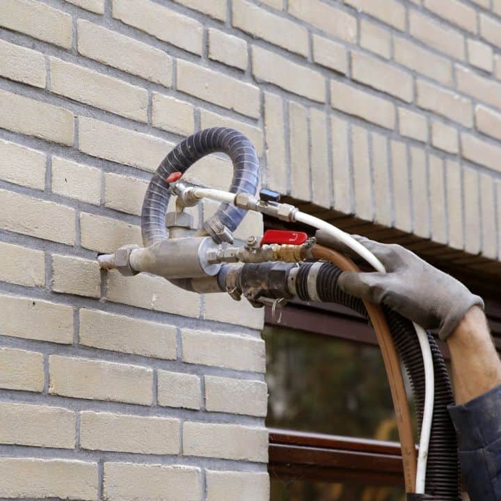 Technician installing Superbead cavity wall insulation into a wall cavity