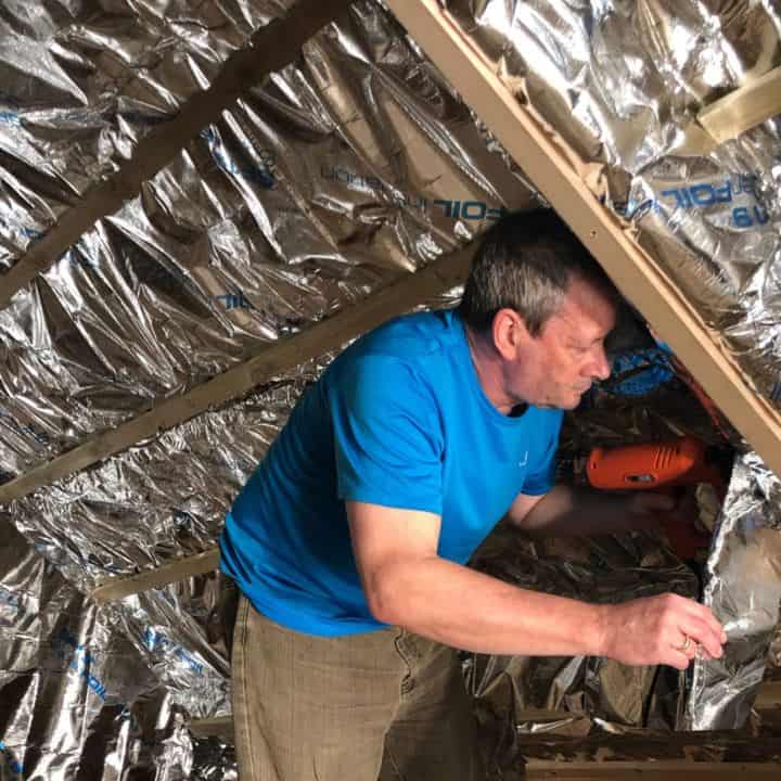 Loft insulation specialist fitting thermal insulation in an attic space.