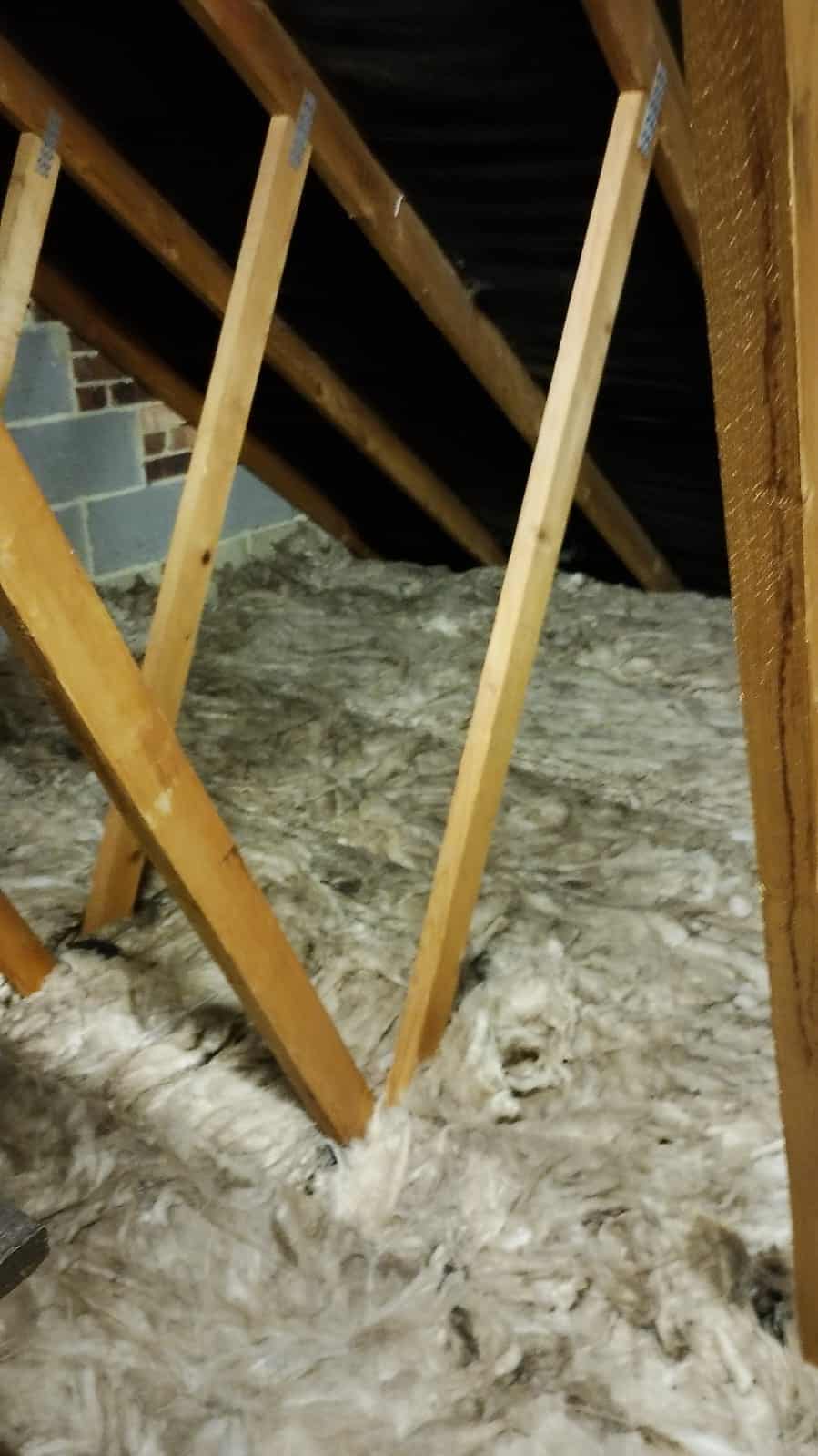 Loft insulation being installed between roof rafters for energy efficiency.