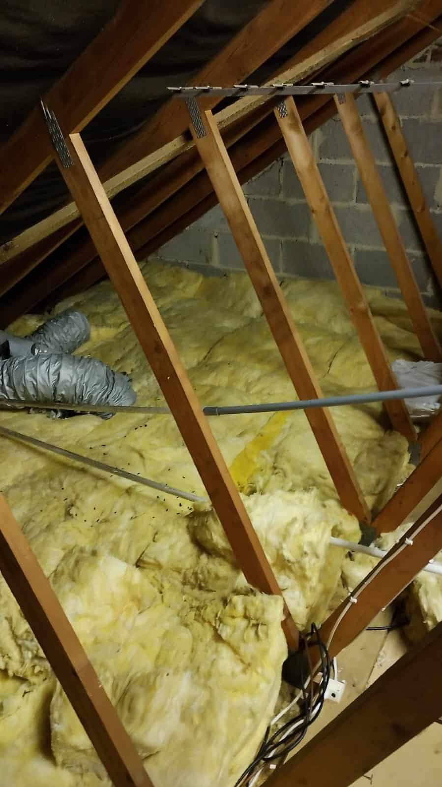 Loft insulation being installed between roof rafters for energy efficiency.
