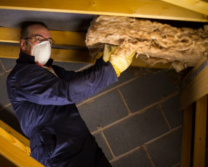A man wearing a mask and gloves exploring in an attic with loft hatches.