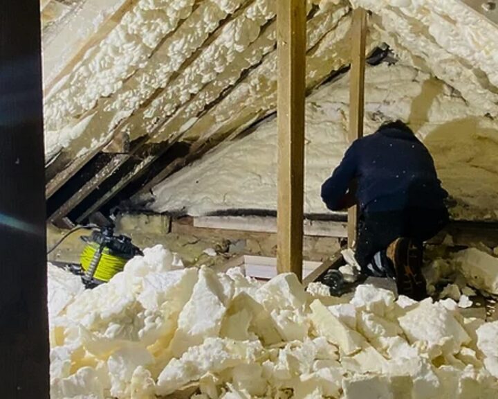 A man is working on an attic with spray foam insulation.